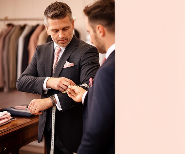 Tailor measuring a man's jacket sleeve in a calm Wolverhampton fitting room